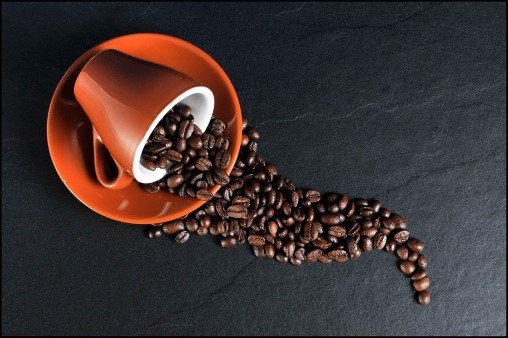 coffee beans spilling out of a brown cup and saucer