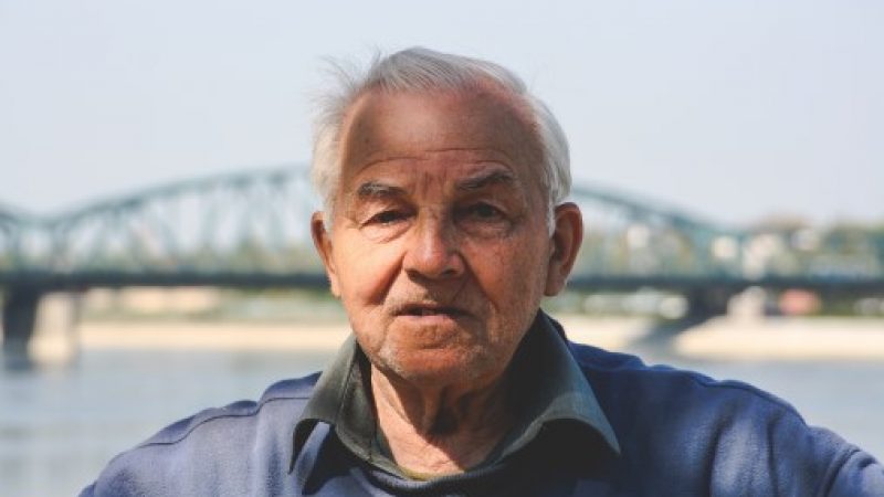 Older man standing in front of a bridge