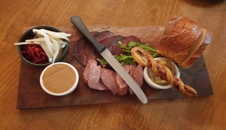 A selection of meats, pickles and breads with a knife on a board at Hinterland Restaurant, Cooran