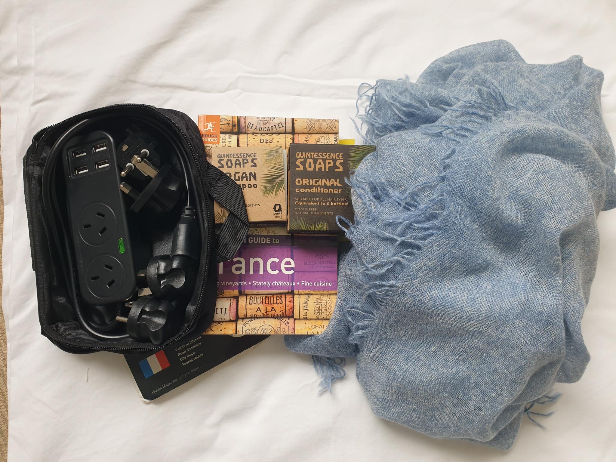 a scarf, a power adaptor, soaps and a guide book are travel essentials